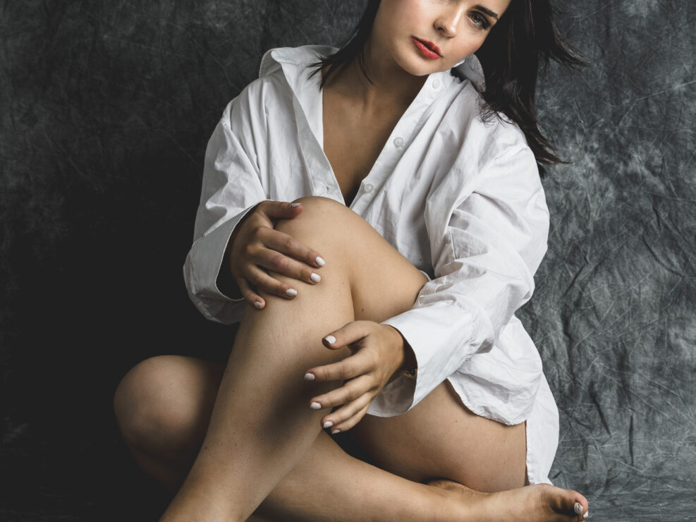 Woman in oversized shirt, seated pose.